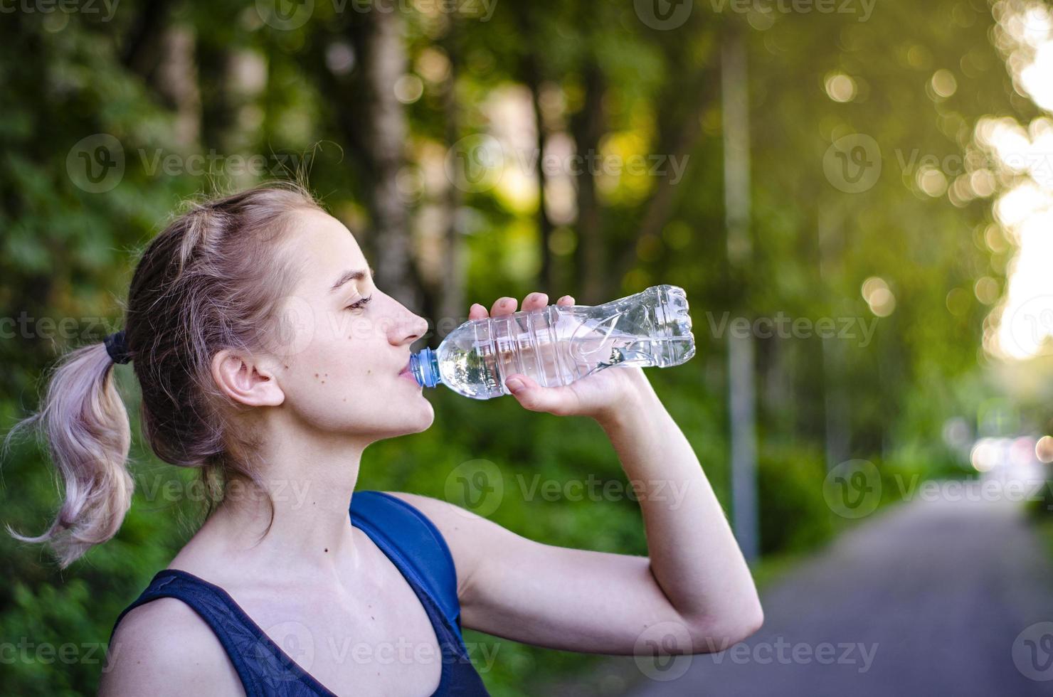 hermosa chica bebiendo agua después del ejercicio. hacer deporte. foto