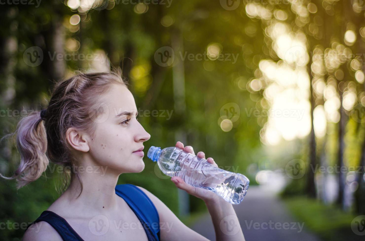 hermosa chica bebiendo agua después del ejercicio. hacer deporte. foto