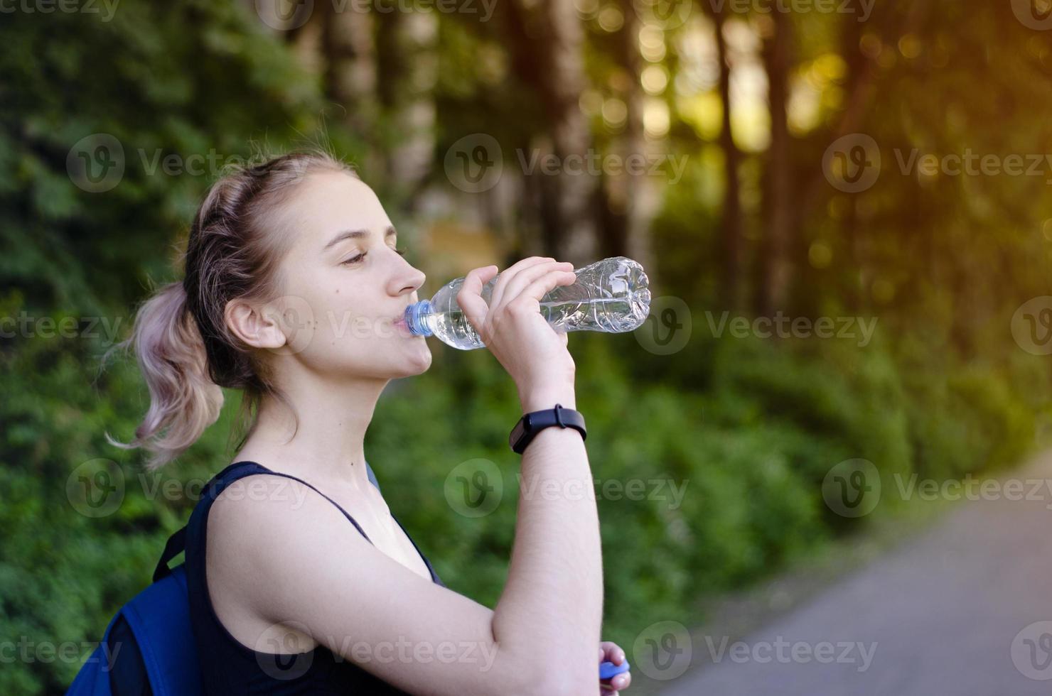 Beautiful girl drinking water after exercise. Playing sport. photo