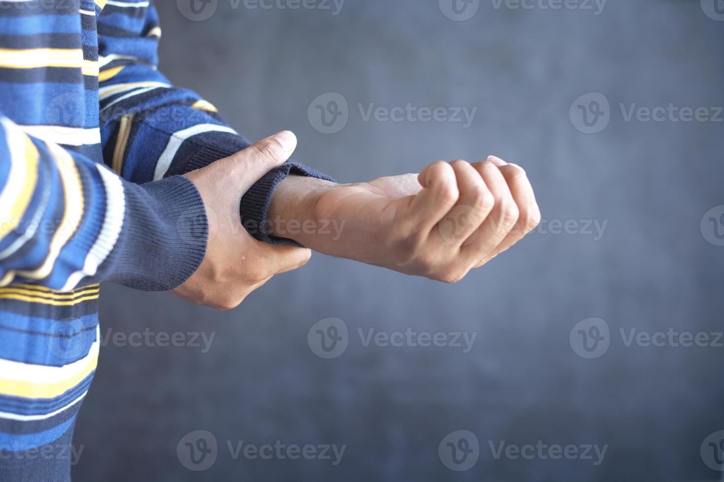 man suffering pain in hand against black background photo