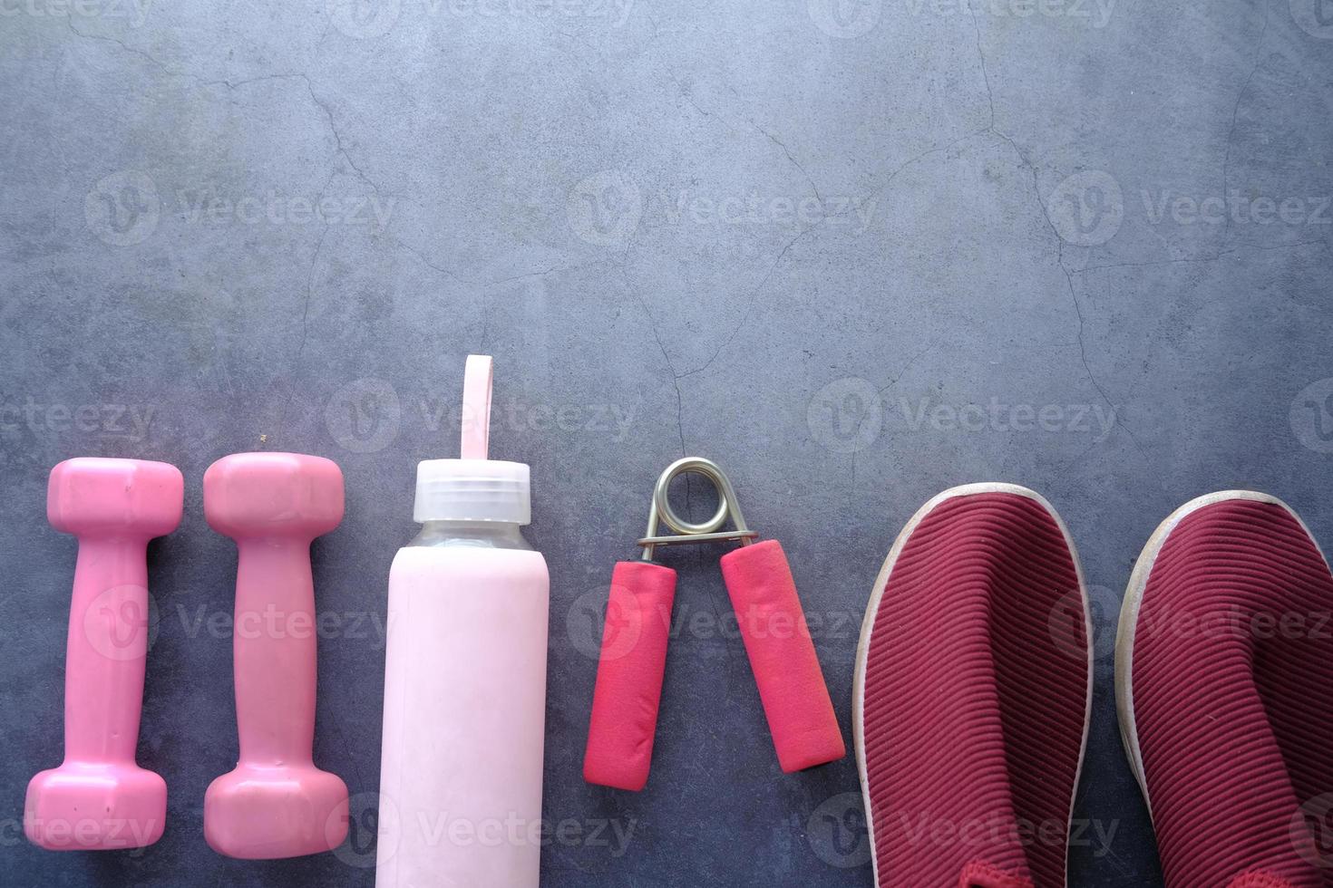 pink color dumbbell, exercise mat and water bottle on black background photo