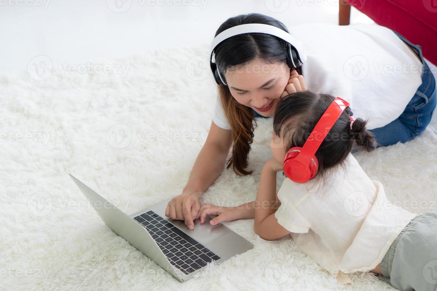 asian mother with teaching child to study from computer at home photo