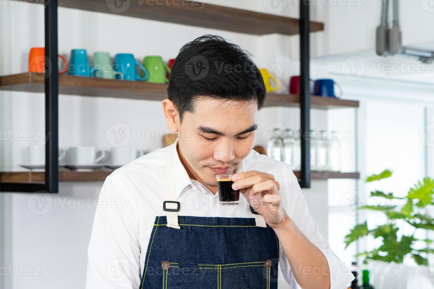joven barista asiático disfruta del olor a café caliente en la cafetería foto