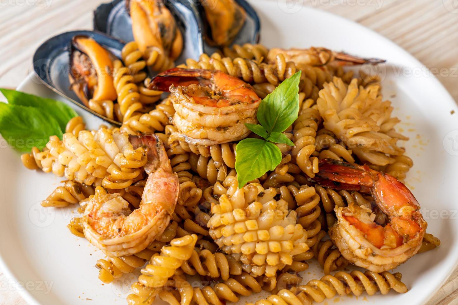 Stir-fried spiral pasta with seafood and basil sauce - fusion food style photo