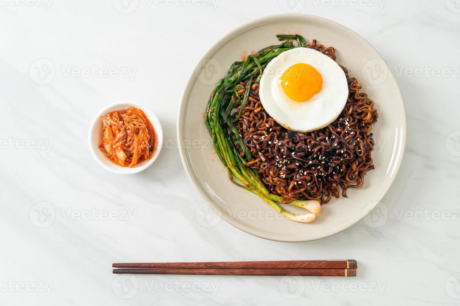 fideos instantáneos secos coreanos picantes con salsa negra casera con huevo frito y kimchi foto