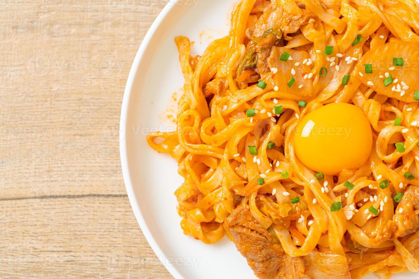 Stir-fried udon noodles with kimchi and pork - Korean food style photo