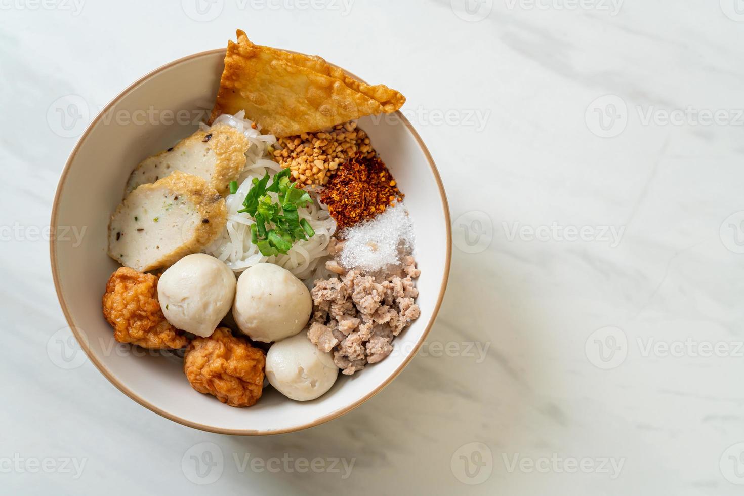 Fideos de arroz planos pequeños picantes con bolas de pescado y bolas de camarones sin sopa - estilo de comida asiática foto