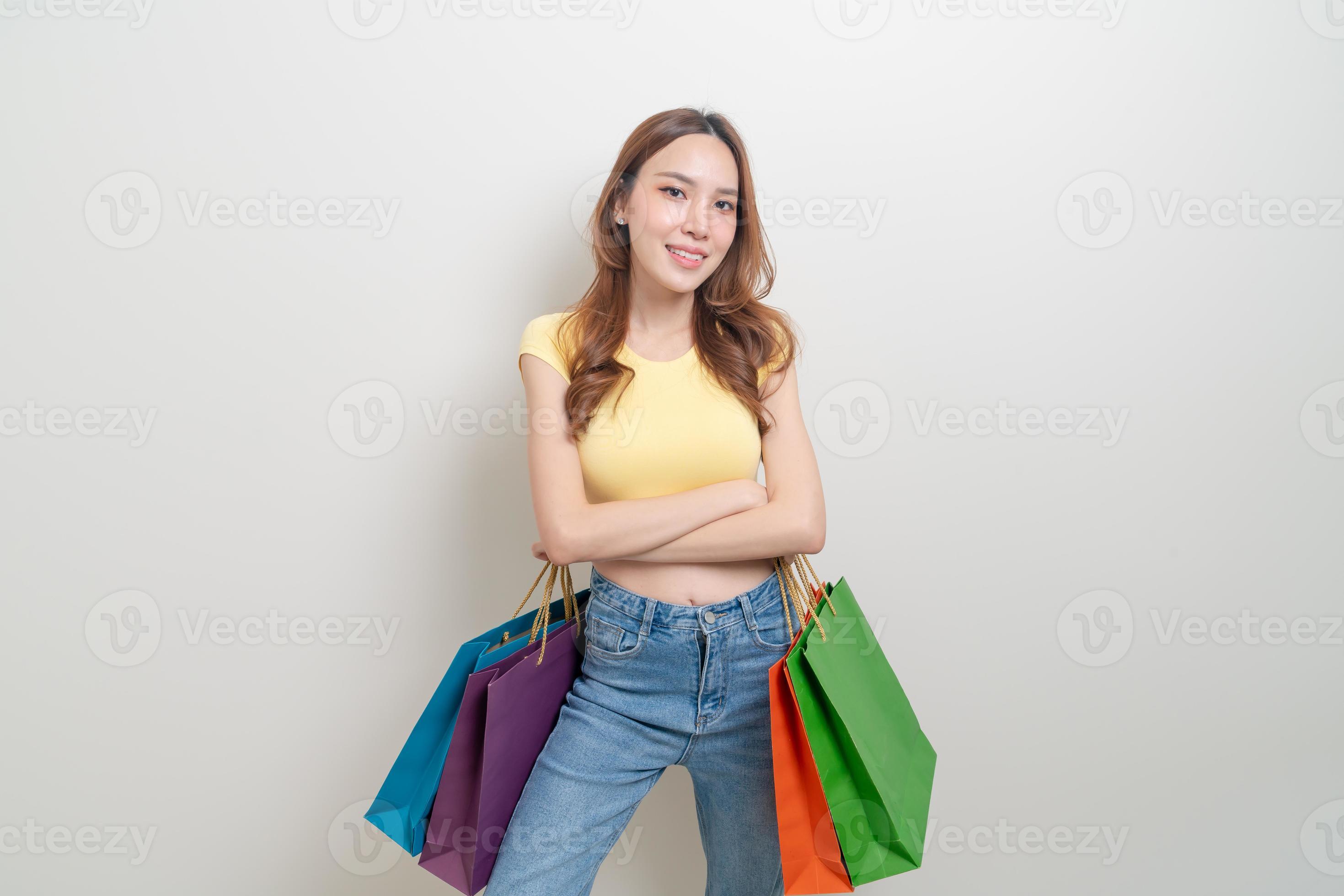 Beautiful Attractive Asian Woman smile and holding luxury shopping bags  feeling so happiness and enjoy with black Friday sale in Shopping  mall,isolated on white background. Shopping Lifestyle Concept Stock Photo