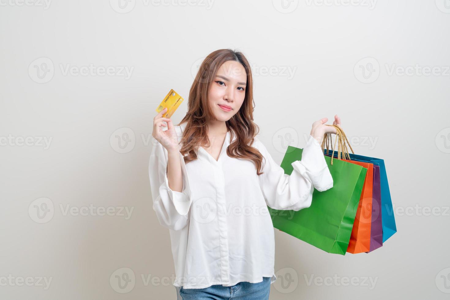 Retrato hermosa mujer asiática sosteniendo una bolsa de compras y una tarjeta de crédito sobre fondo blanco. foto