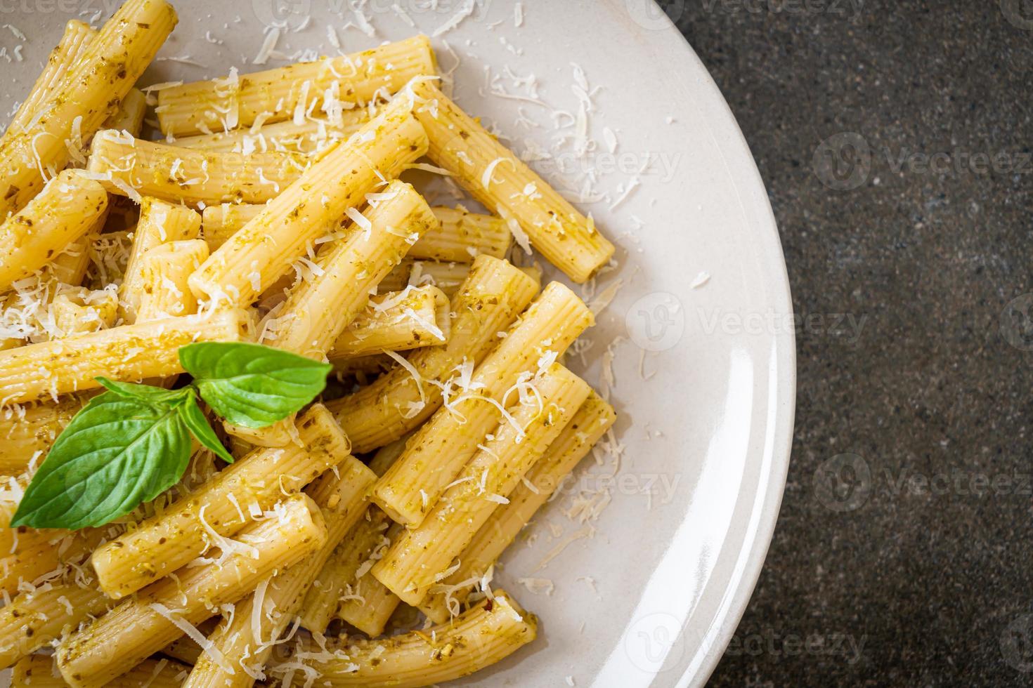 pasta al pesto rigatoni con queso parmesano - comida italiana y estilo vegetariano foto