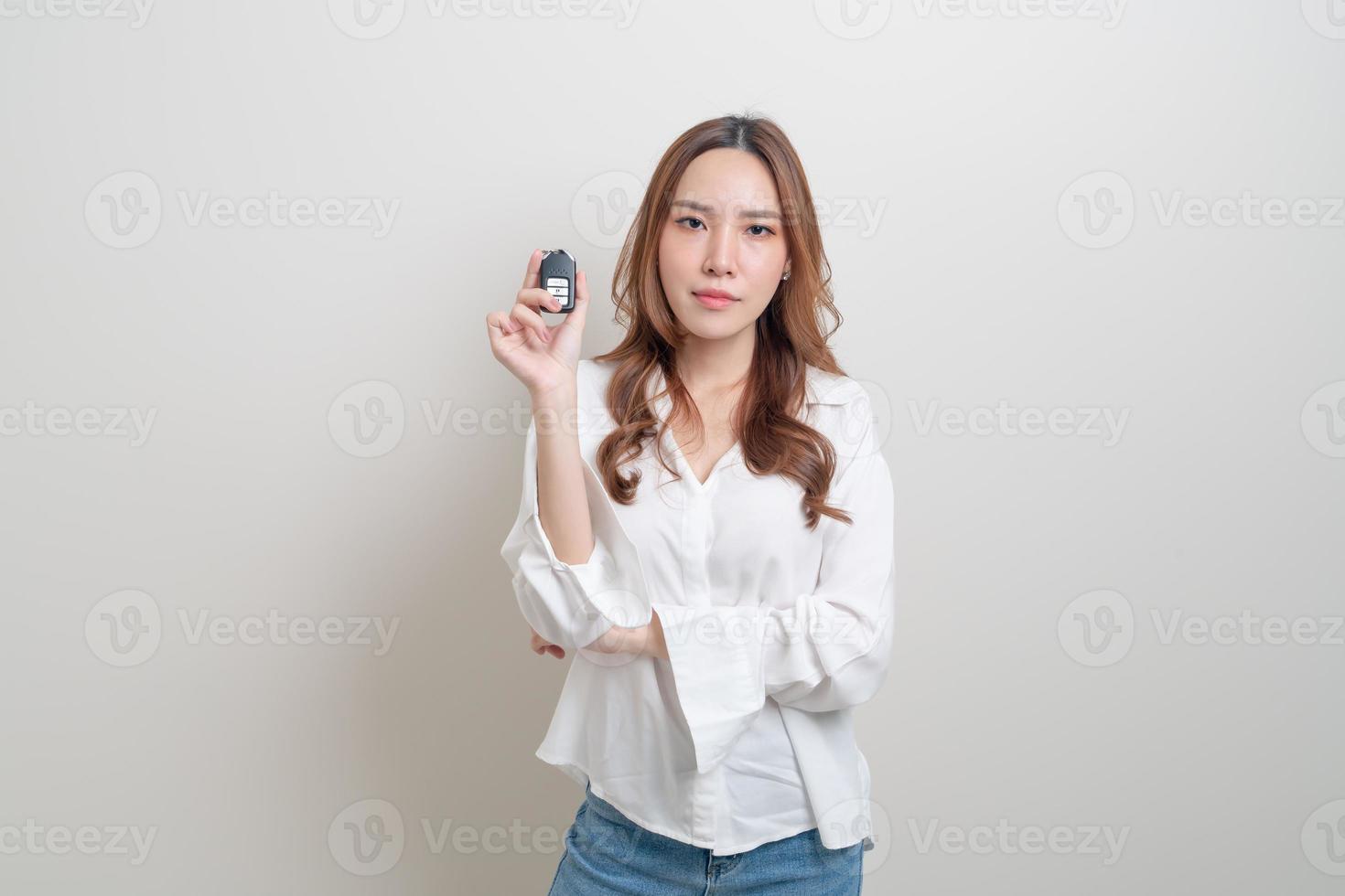Retrato hermosa mujer asiática sosteniendo la llave del coche sobre fondo blanco. foto