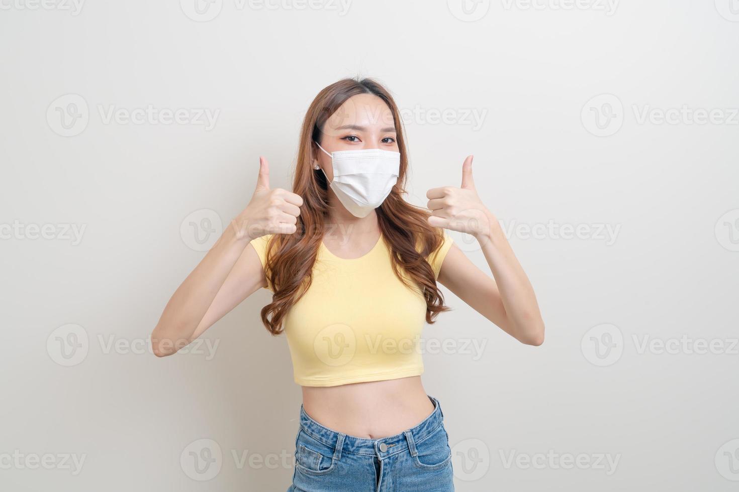 Retrato hermosa mujer asiática con una máscara con signo de mano ok o de acuerdo sobre fondo blanco. foto