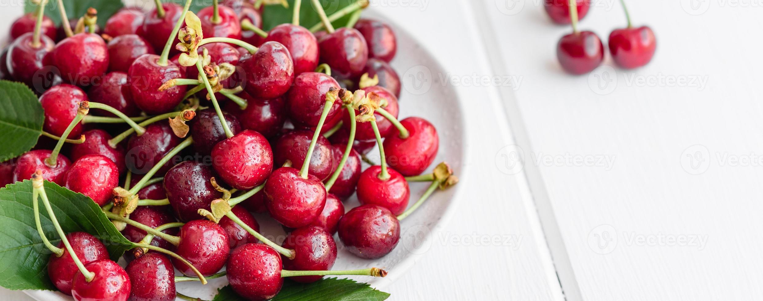 Frescas y deliciosas bayas de cerezo rojo brillante rasgadas en el jardín de verano foto