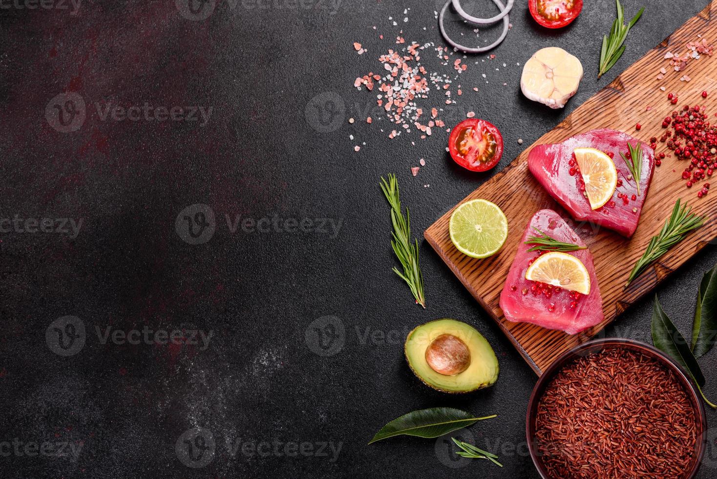 Fresh tuna fillet steaks with spices and herbs on a black background photo