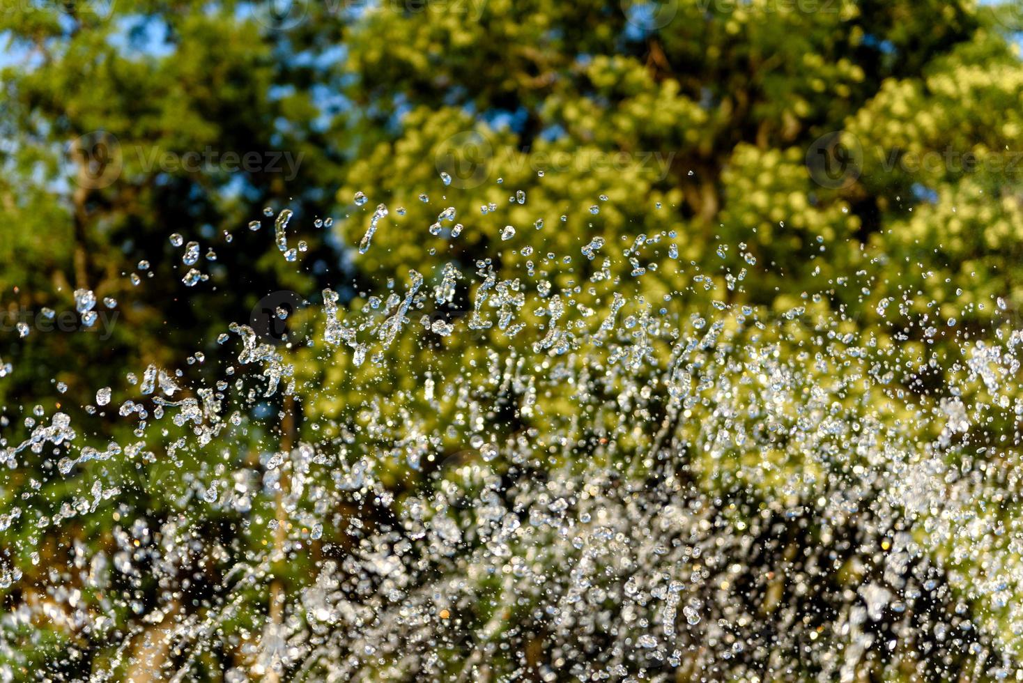 Selective focus on spray of urban fountain and blurred background photo