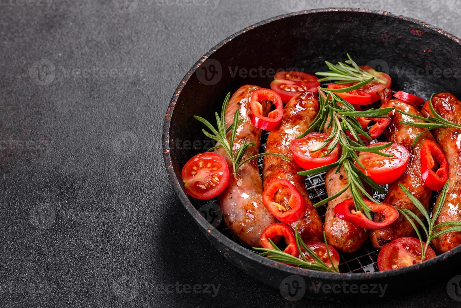 Salchichas a la parrilla con verduras y especias sobre fondo negro foto