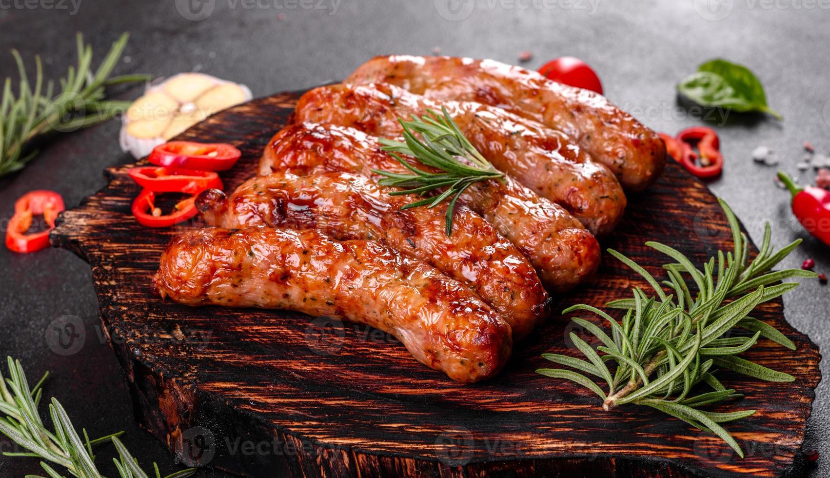 Salchichas a la parrilla con verduras y especias sobre fondo negro foto