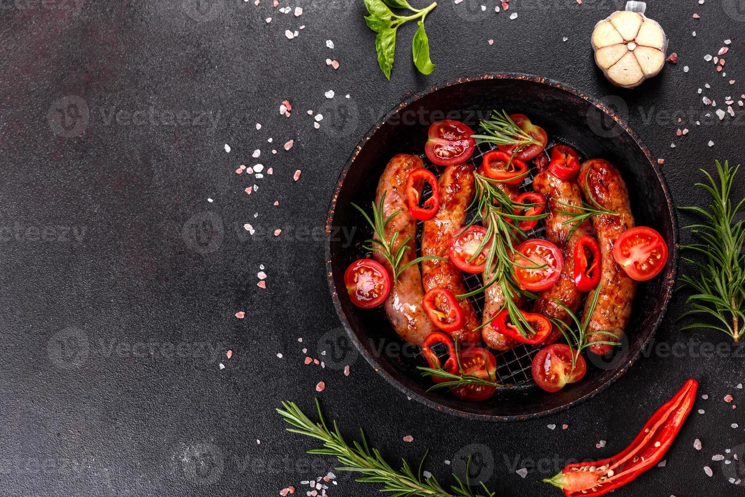 Grilled sausages with vegetables and spices on black background photo