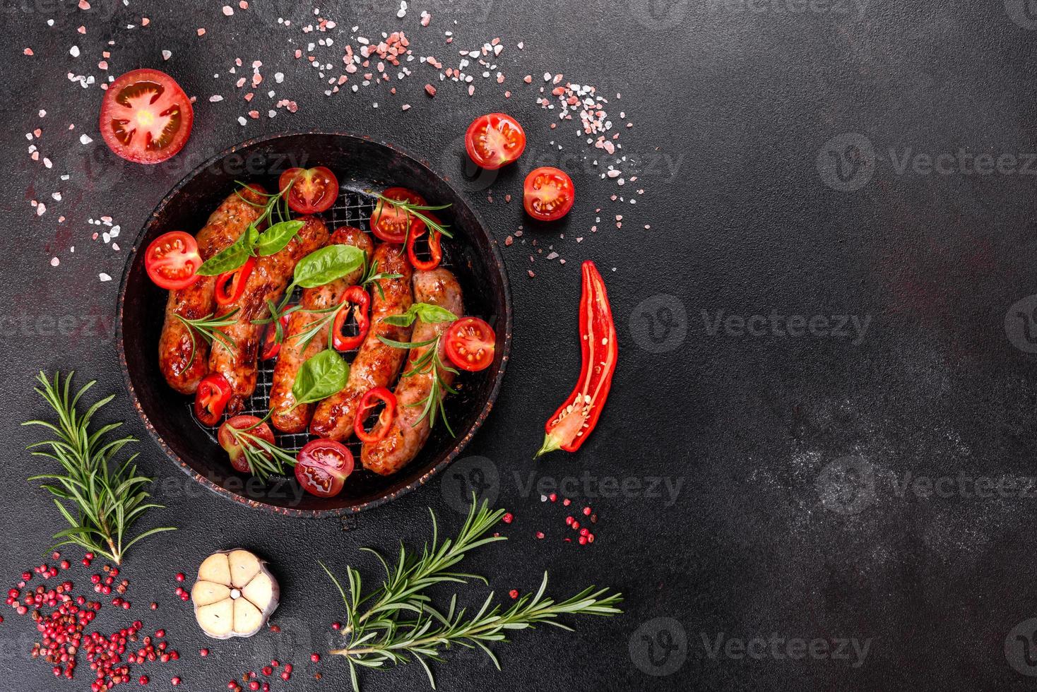 Salchichas a la parrilla con verduras y especias sobre fondo negro foto