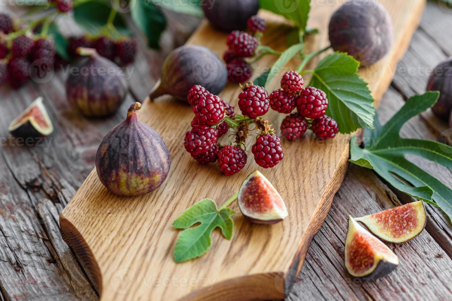 Higos frescos jugosos y moras sobre un fondo oscuro foto