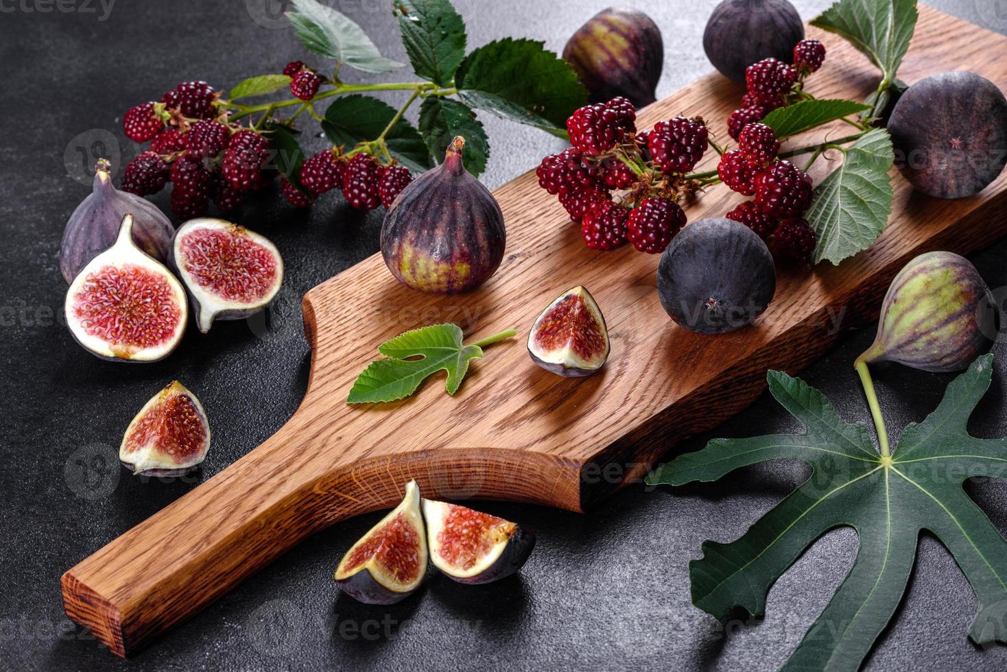 Fresh juicy figs and blackberries on a dark background photo