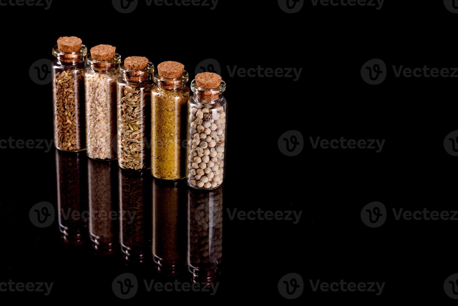 Small glass jars with corks with various spices inside photo