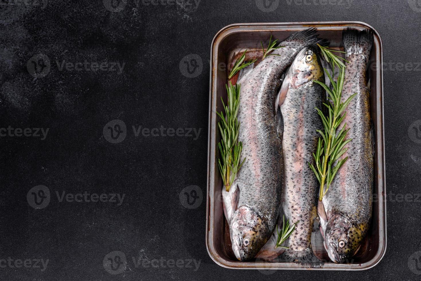 Raw trout lie on a black stone chopping board on a dark concrete table photo