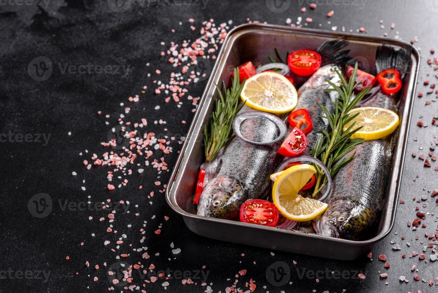 Raw trout lie on a black stone chopping board on a dark concrete table photo