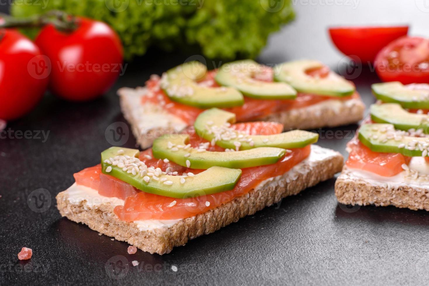 delicioso sándwich fresco con pescado rojo, mantequilla, pan y aguacate foto