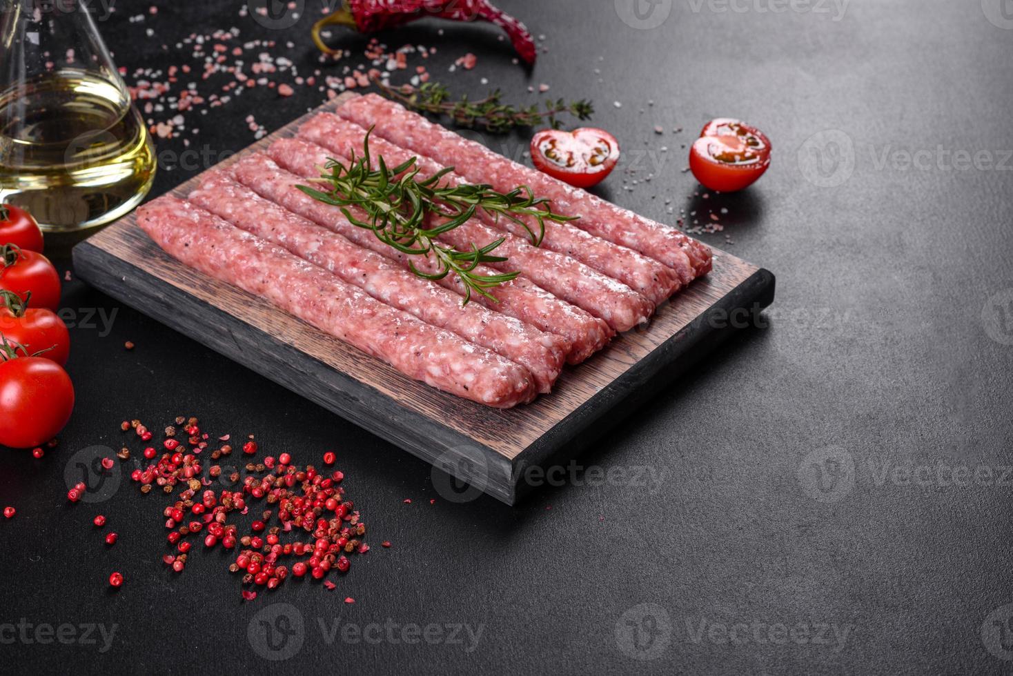 Salchichas de cerdo cruda fresca con especias sobre una tabla de cortar de madera foto