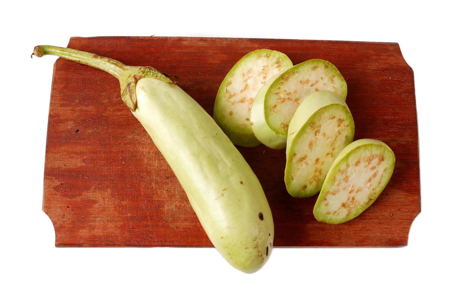 Green eggplant on a wooden cutting board isolated on a white photo