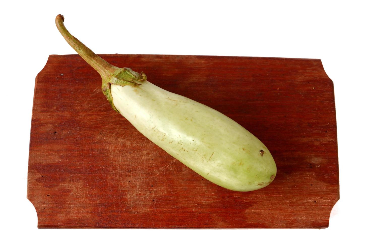 Green eggplant on a wooden cutting board isolated on a white photo