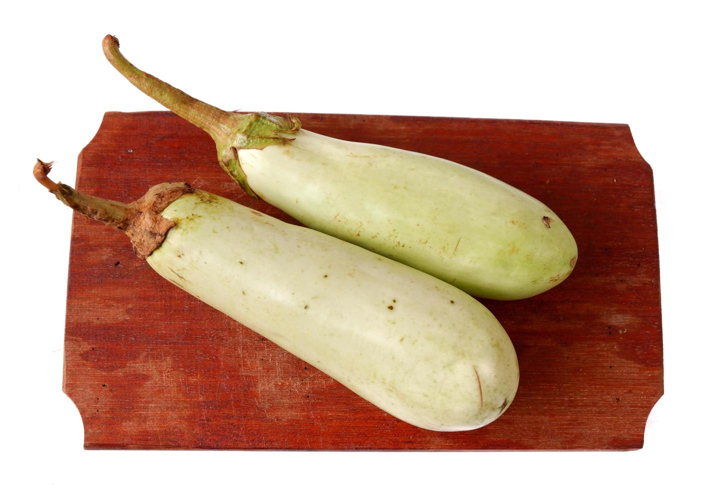 Green eggplant on a wooden cutting board isolated on a white photo