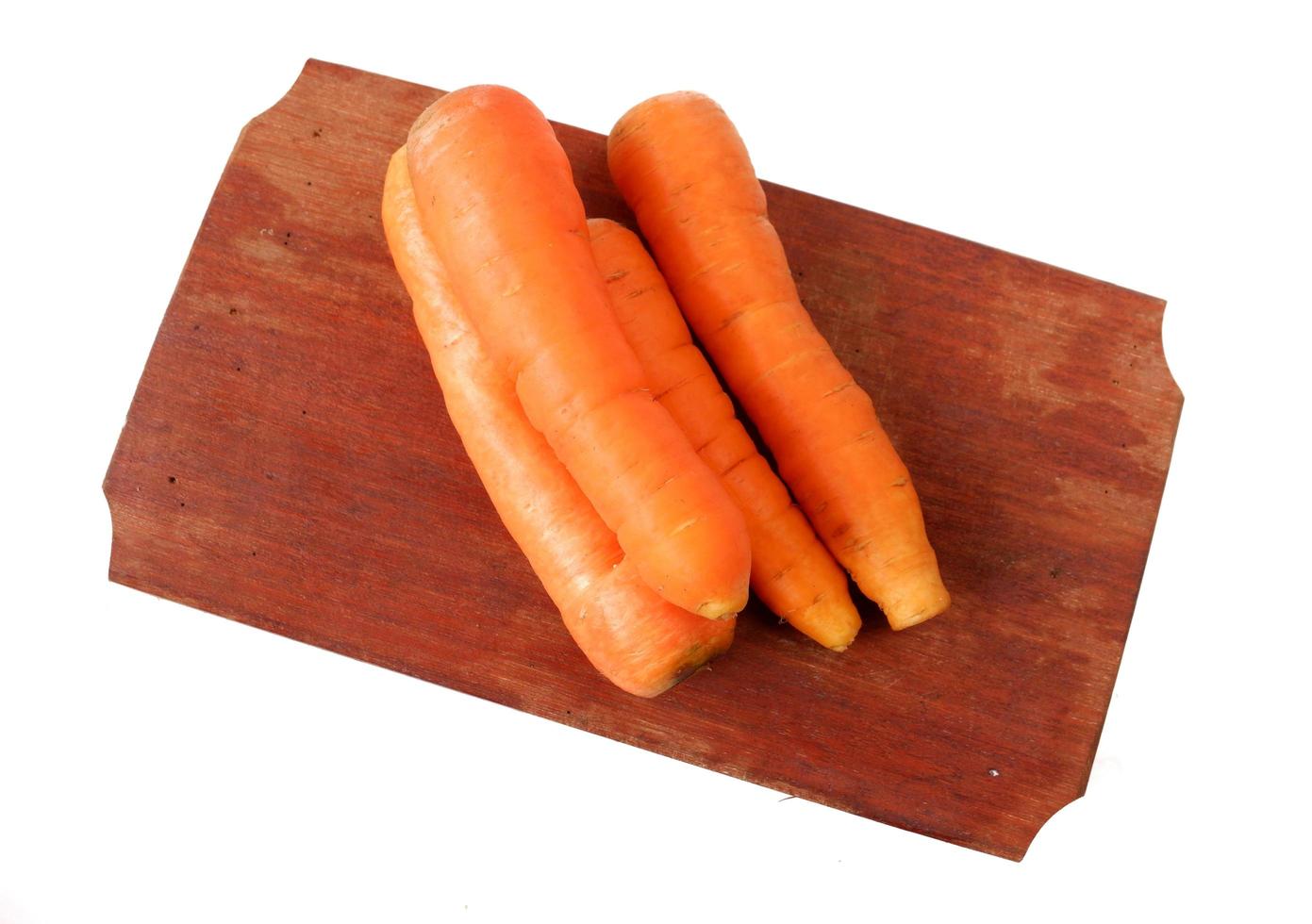 Zanahorias en una tabla de cortar de madera aislado sobre un fondo blanco. foto