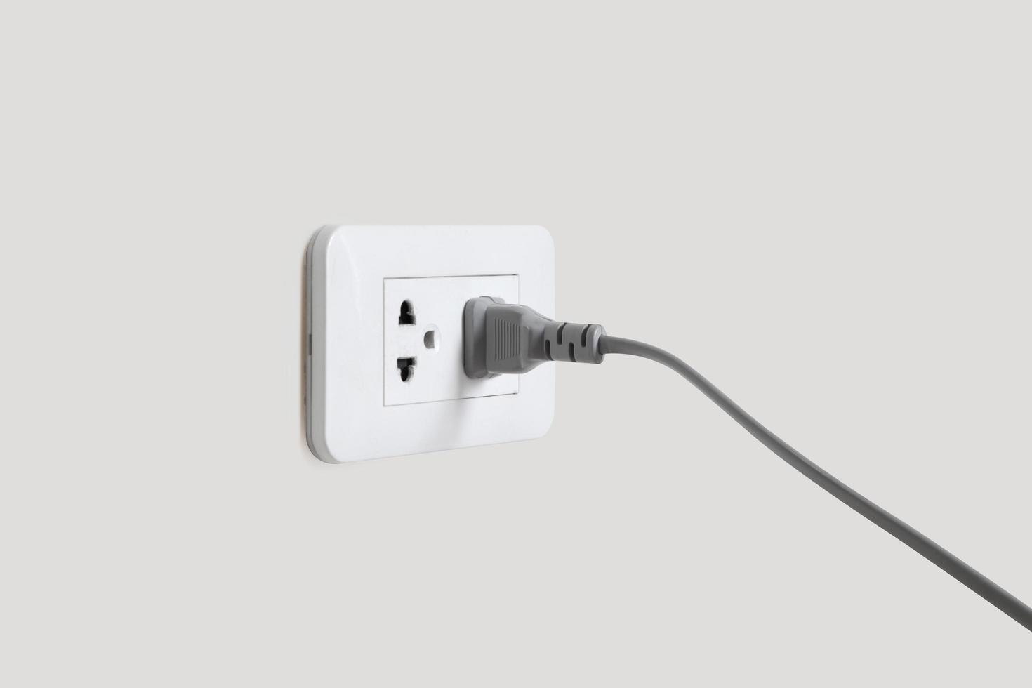 Gray plug in electric cord to a plastic electric socket photo