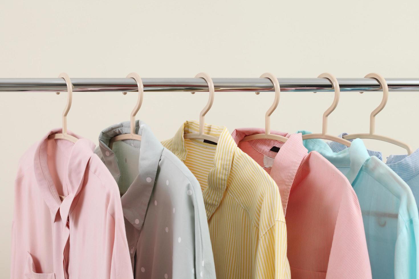 Camisas color pastel colgadas en una rejilla en la tienda y espacio libre para texto foto