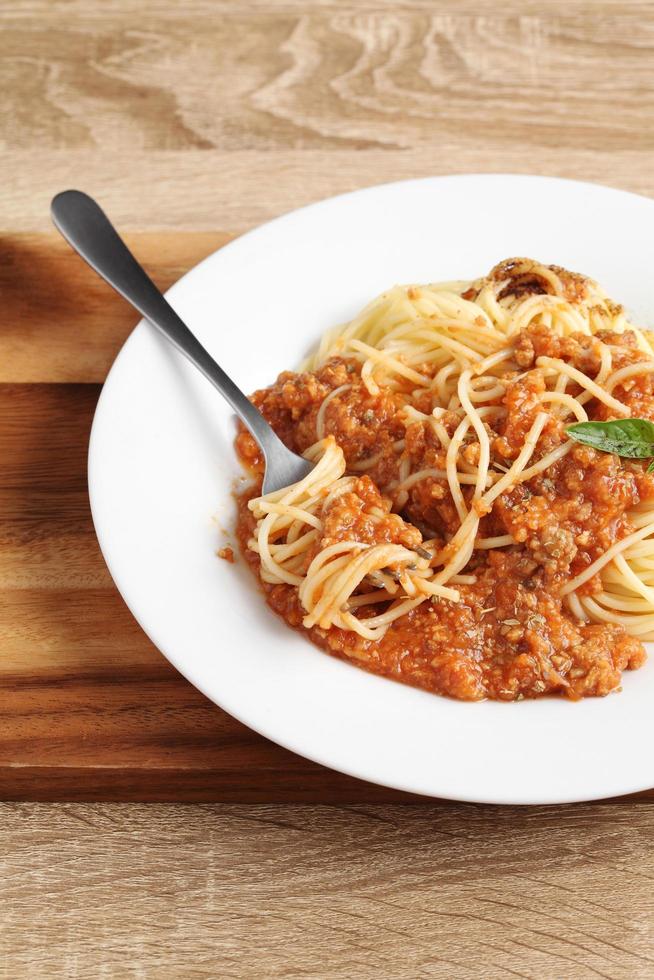 Close up a fork with spaghetti and red sauce in dish photo