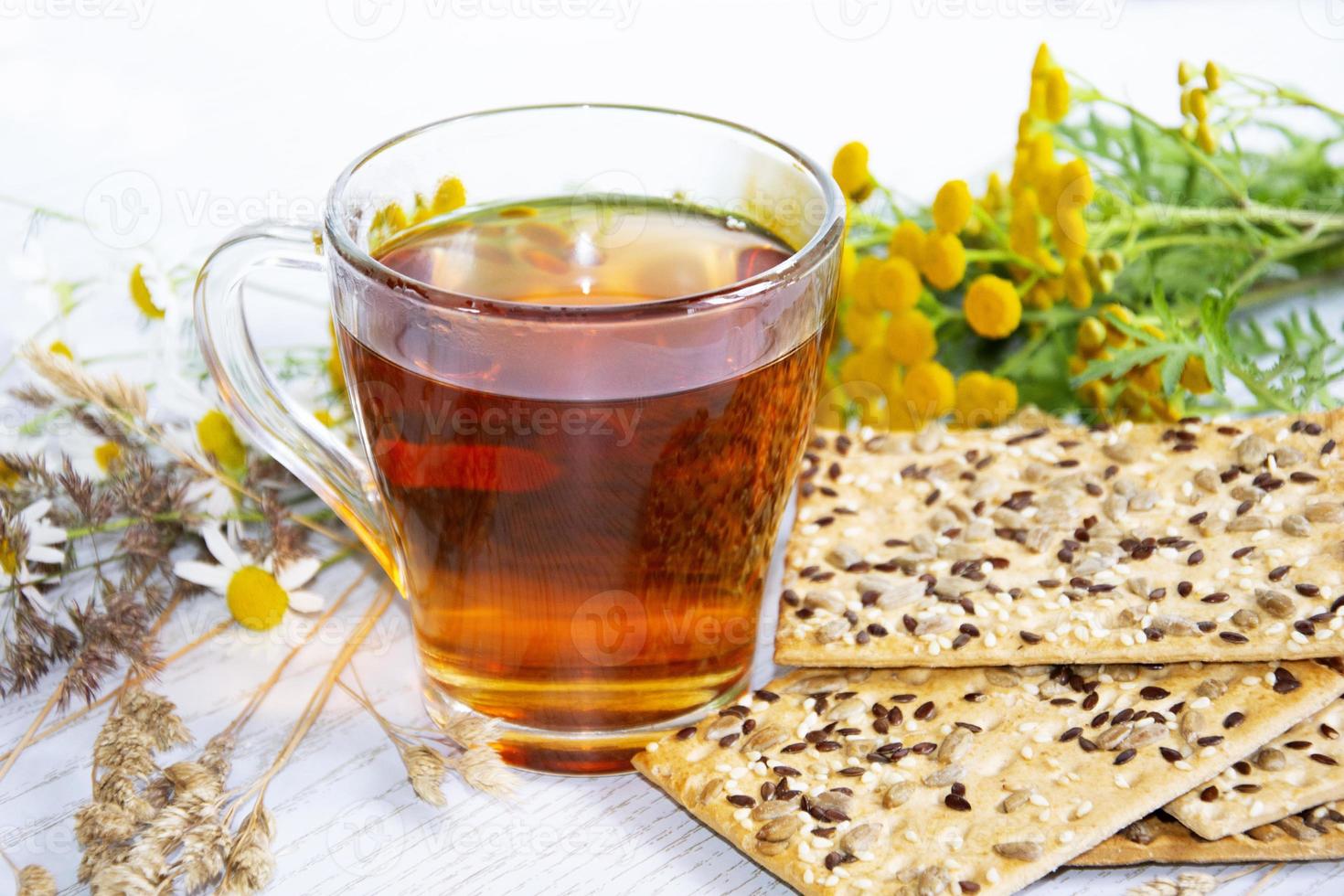 Glass cup with hot tea, cookies, and flowers photo