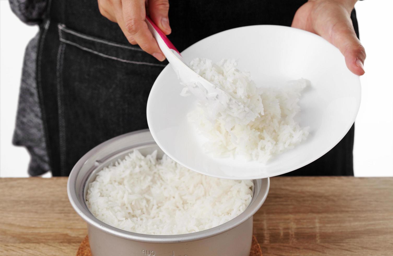 Woman use rice spoon to scoop rice from pot photo