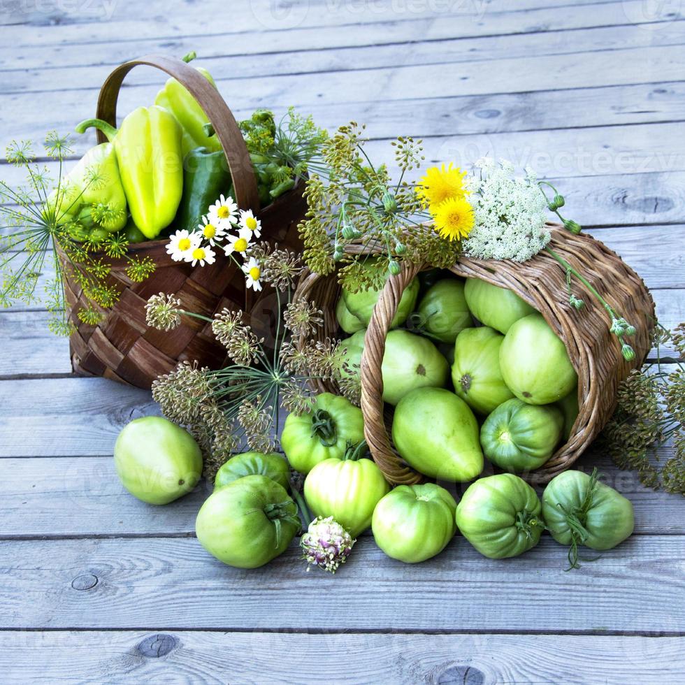 Vegetables in a basket and a bouquet of wild flowers on background photo