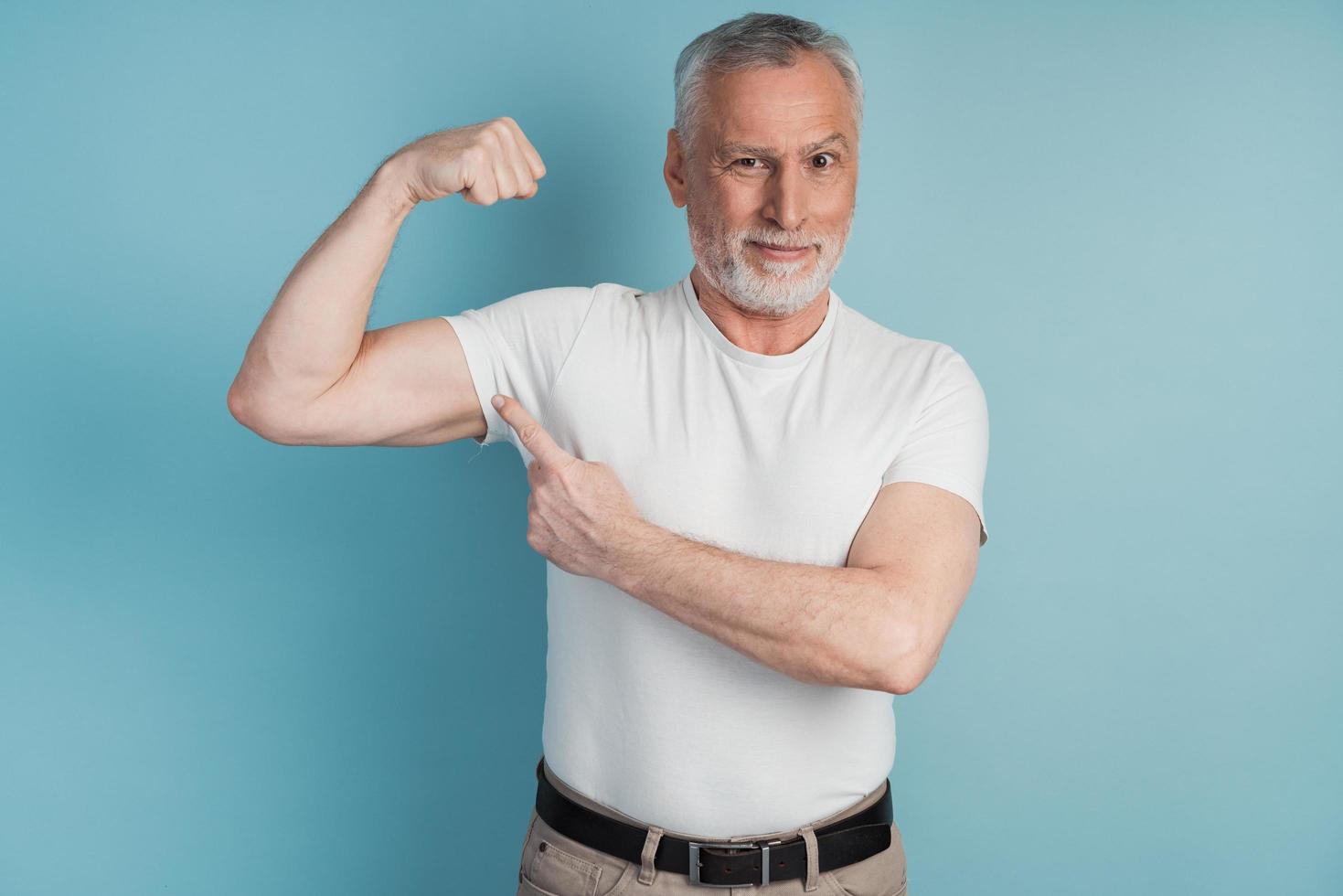 Senior hombre barbudo mostrando músculos vistiendo camiseta blanca pose foto