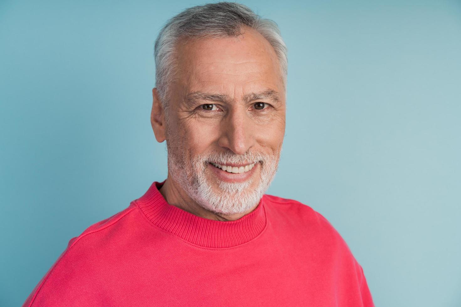 Close-up view, senior man smiling on blue background photo