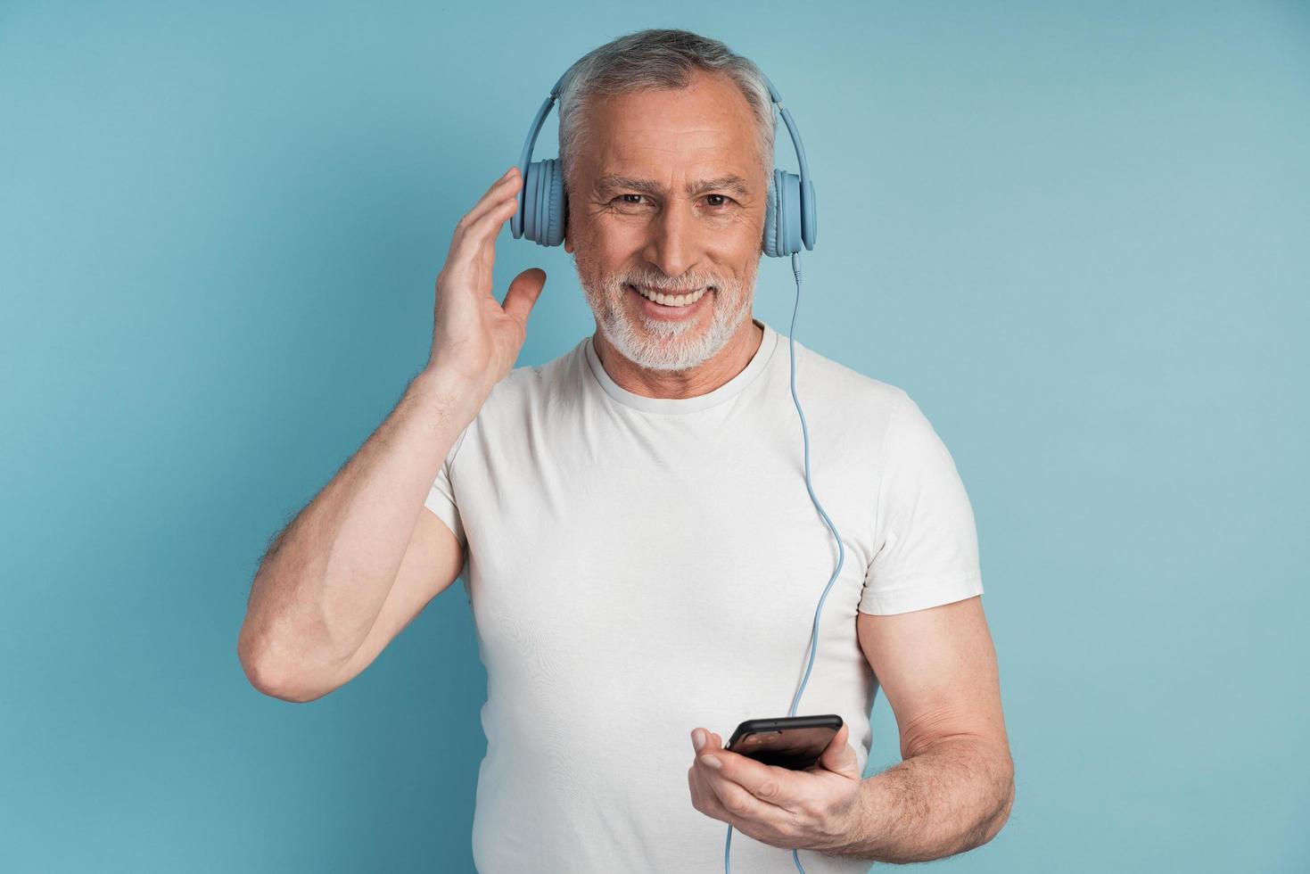 Positive, smiling senior man and beard wears headphones photo