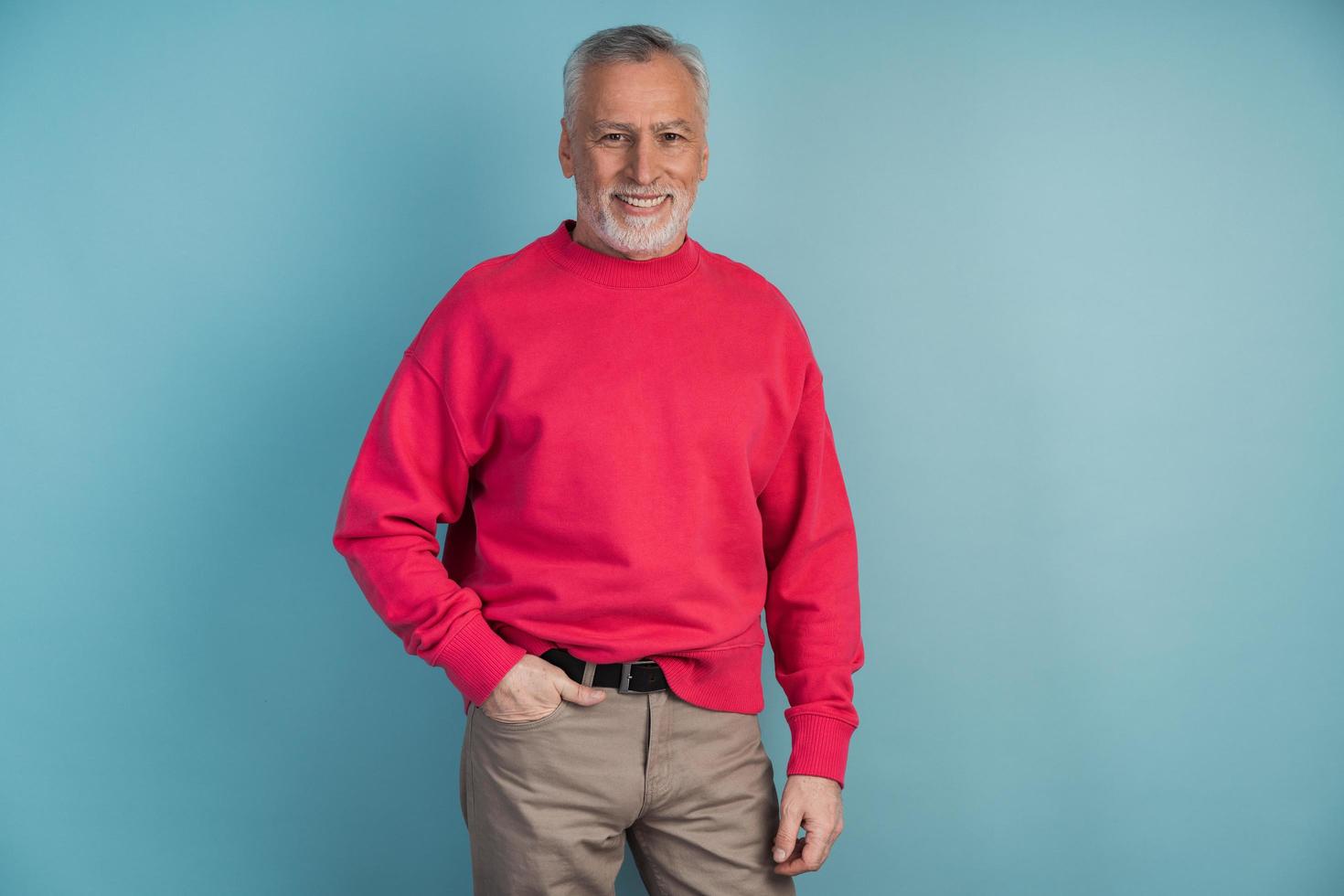 Handsome, mature man in a crimson pullover posing on a blue background photo