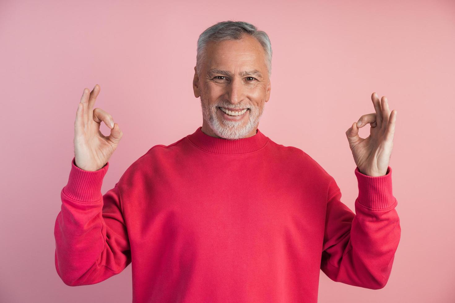 Smiling man meditating on a pink background photo