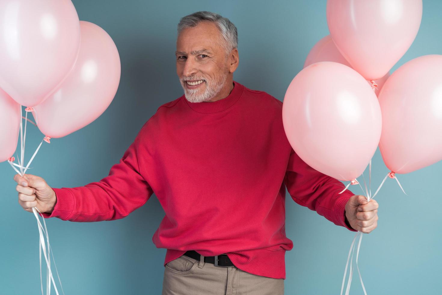 foto de un atractivo hombre mayor sosteniendo globos rosas