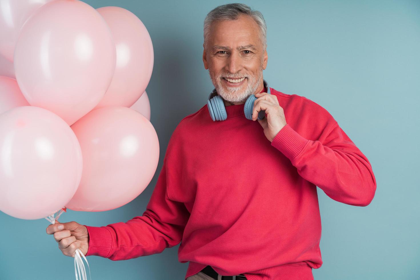 A smiling, older bearded man wears headphones photo