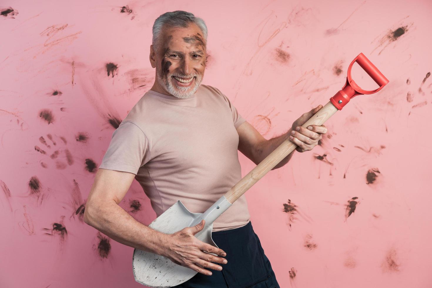 divertido, alegre, anciano sosteniendo una pala como si sostuviera una guitarra foto