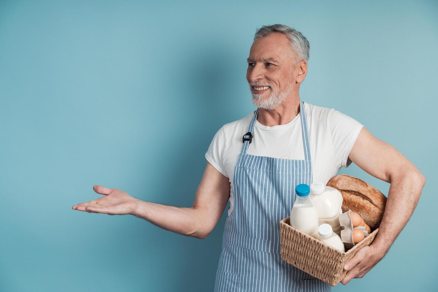 Positive man with gray hair and beard holding food basket photo