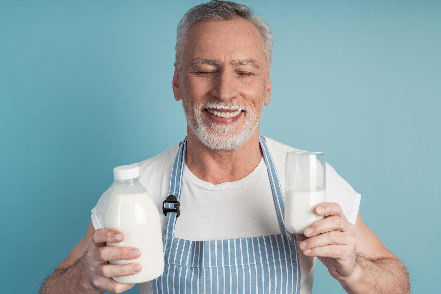 Cute grandfather with gray hair and beard holds a bottle of milk photo